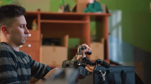 Man Adjusting Camera Equipment in Workshop or Studio Focusing on Device Controls