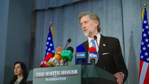 Man Speaking at Podium with Flags