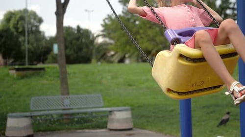 Une petite fille blonde fait des balançoires dans le parc de Green City Un petit enfant aime se balancer sur le terrain de jeu