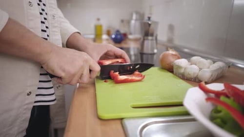 Unerkennbarer kaukasischer Mann, der zu Hause Gemüse hackt