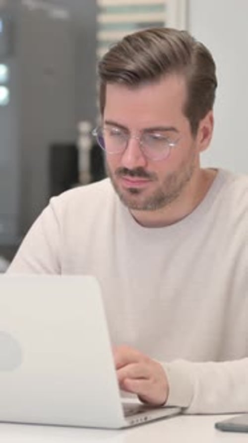 Joven frustrado molesto mientras trabajaba en una computadora portátil