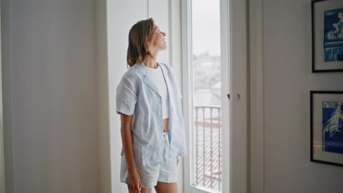 Beautiful Woman in Pajamas Standing near Open Window