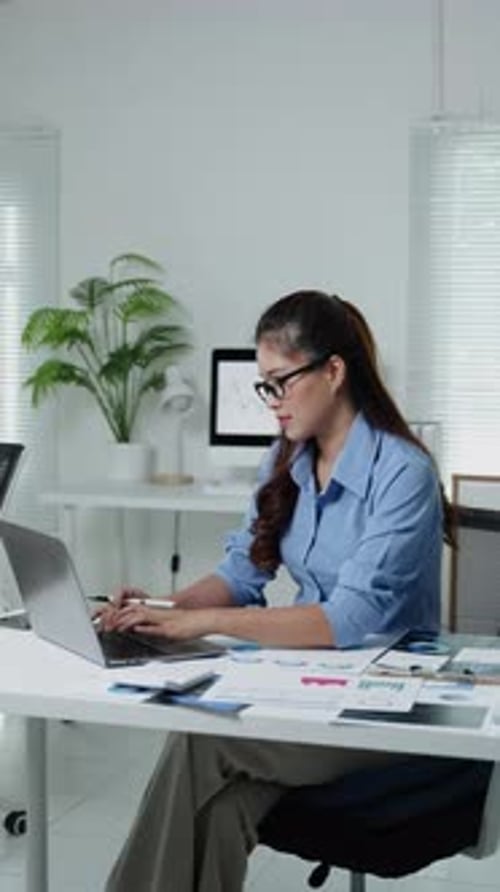 Woman Working on Laptop at Desk in Bright Office
