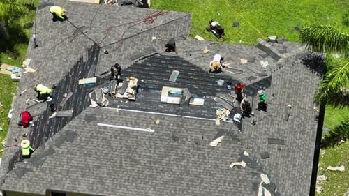 Construction Workers Installing Asphalt Shingles As House Roof Covering Building of Florida Home