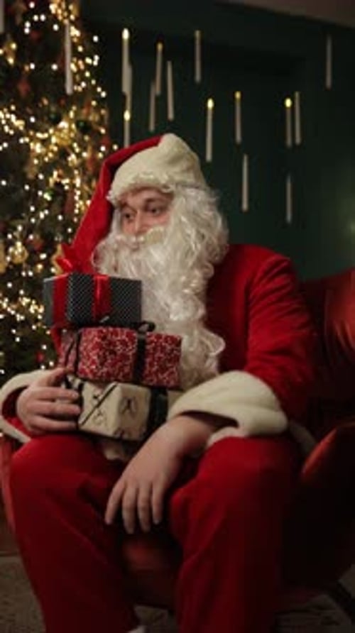 Man in Santa Claus Suit with Gifts Near Decorated Christmas Tree Vertical Video