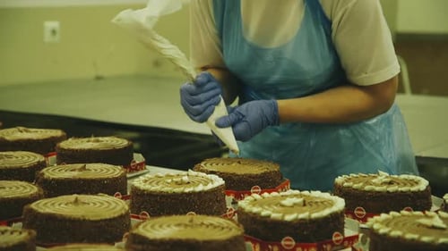 Chocolate Cakes Being Decorated with White Icing