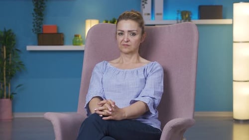 Woman Sitting Still in Chair in Blue Room
