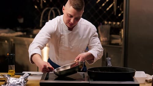 Chef in the Kitchen Pouring Oil Over Seared Beef Steak with Rosemary in Frying Pan