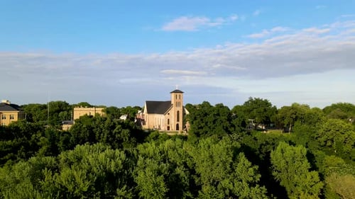 Vista aérea giratoria de la iglesia de Notre Dame, Chippewa Falls, Wisconsin, rodeada de vegetación pura.