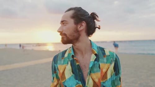 Young man standing on the beach at sunrise