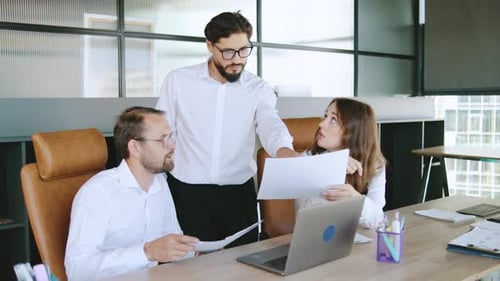 Group of Professionals Discussing Project Details in a Modern Office Setting During Daytime Hours
