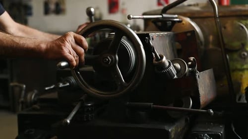 Close-up of worker's hands operating industrial machinery in workshop.