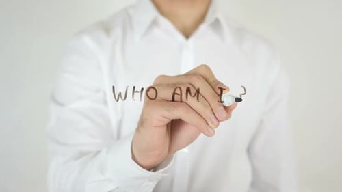 Man Writing Who Am I Question on Glass