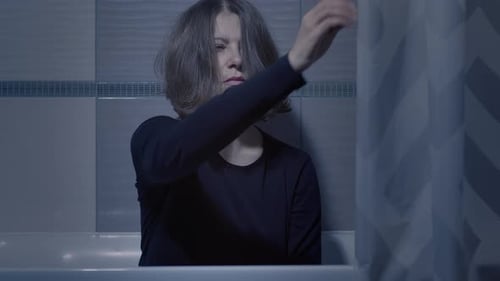 Distressed Woman Sits in Bathtub at Night