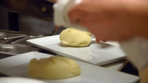 Chef plating mashed potatoes in commercial kitchen