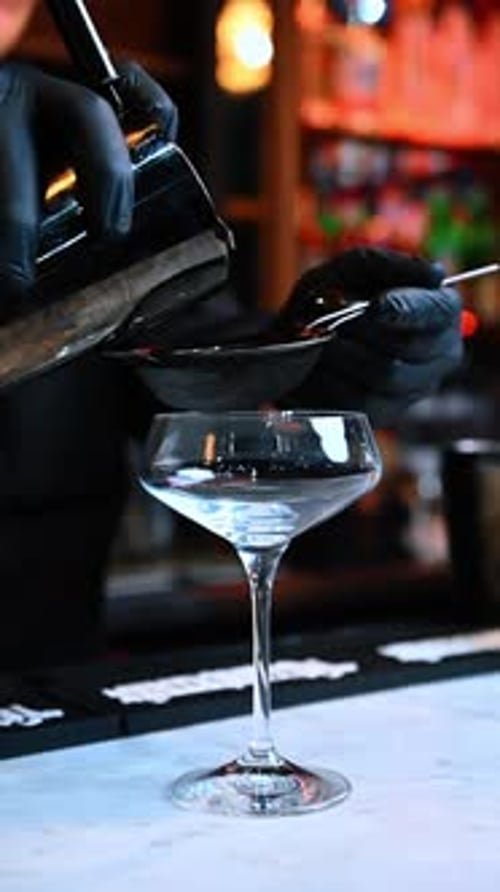 Bartender Pours Cocktail Through Strainer Into Glass