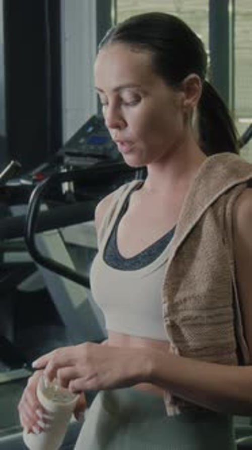 Tired Woman Having Water Break after Training in Gym