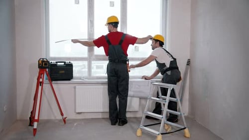 Wohnungsreparaturarbeiter messen das Fenster im Zimmer