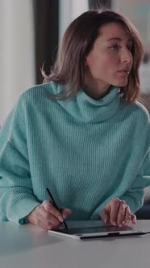 A Woman in a Blue Sweater Uses Her Tablet at a Cozy Table