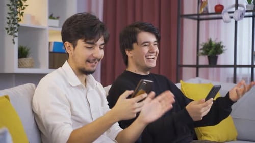 Two Young Adults Chatting While Using Cell Phones