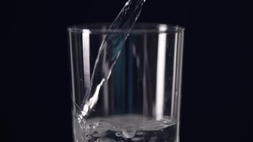 Kristallklares Wasser fließt sanft in das Glas und wird detailliert eingefangen.