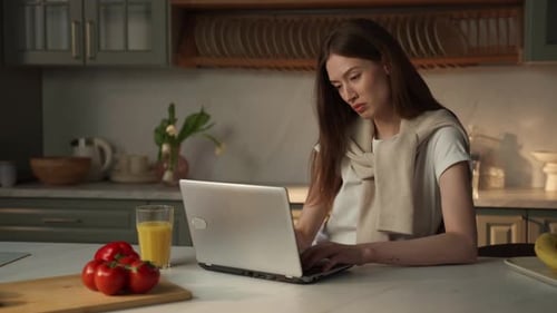 Young Woman Works on Laptop in Kitchen