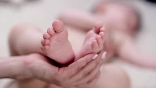 Adult Holding Tiny Baby Feet in Hands
