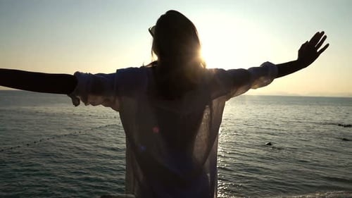 Woman stretching arms admiring golden sunset on beach in super slow motion