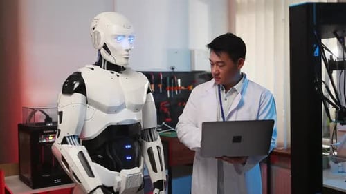New York, 27. April 2020: Mitarbeiter eines cybermetischen Roboters arbeitet mit einem asiatischen Entwickler zusammen, der einen Laptop verwendet
