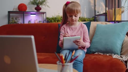 Girl Writing in Notebook on Couch at Home