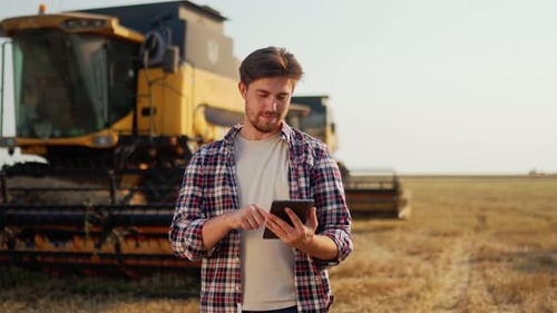 Young Man Using Tablet on Harvested Field