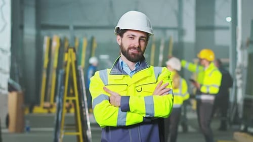 Portrait Shot of Handsome Young Caucasian Male in Helmet and Yellow Uniform Standing at Plant and