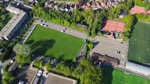Vue aérienne d'en haut d'un terrain de sport verdoyant avec des marques blanches entouré d'arbres et de sentiers