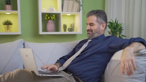 Man Working on Laptop Relaxing on Couch