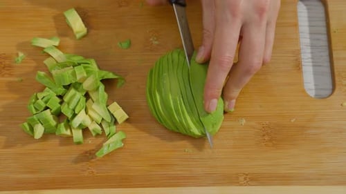 Woman Cutting Fresh Avocado on Wooden Board