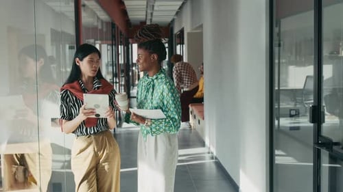 Positive Businesswomen with Docs Chatting in Office Hallway