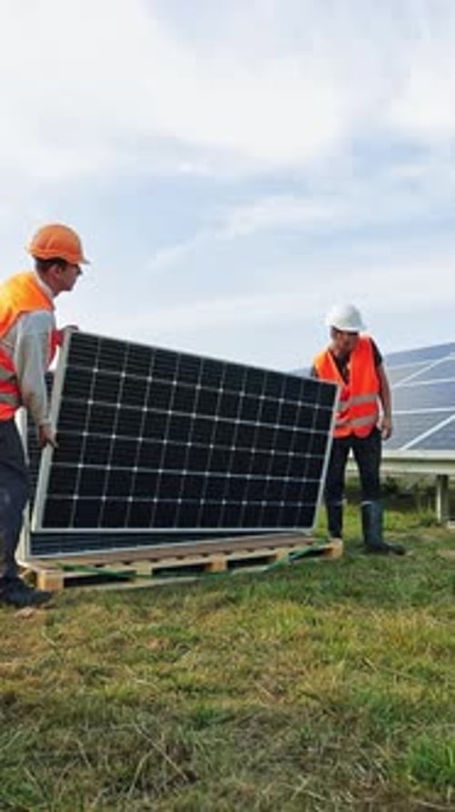 Neue Sonnenkollektoren auf dem Gras. Arbeiter, die Photovoltaikmodule für erneuerbare Energien installieren.