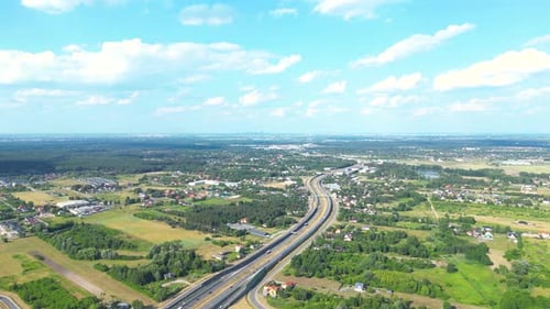 Aerial view of road in green meadows at sunset in summer. Top view from drone of rural road, forest.