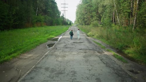Boy Adjusting Backpack While Walking with Sister on Rural Paved Road