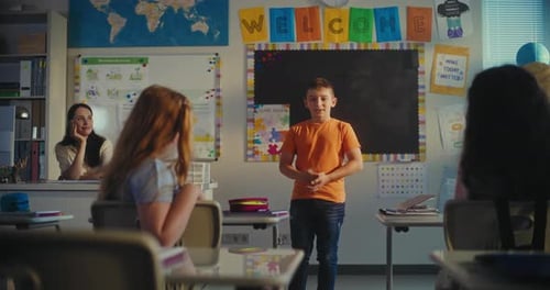 Primary School Boy Showcasing Knowledge of Ecology in Front of Class and Female Teacher