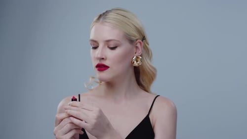 Glamorous Woman Applying Red Lipstick in Studio Setting