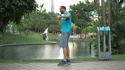 Young Male Jogger Drinking Water After Workout in City Park 30s