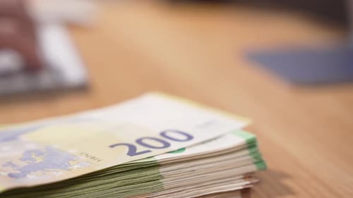 Stack of Euro Notes on Table by Keyboard