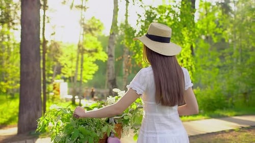 Happy Beautiful Traveler Tourist Woman Cycling Bicycle with Basket of Spring White Apple Tree