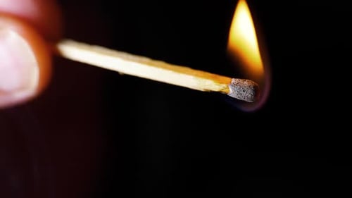 HD Super slow motion cinematic shot of a match being lit, in a dark room.