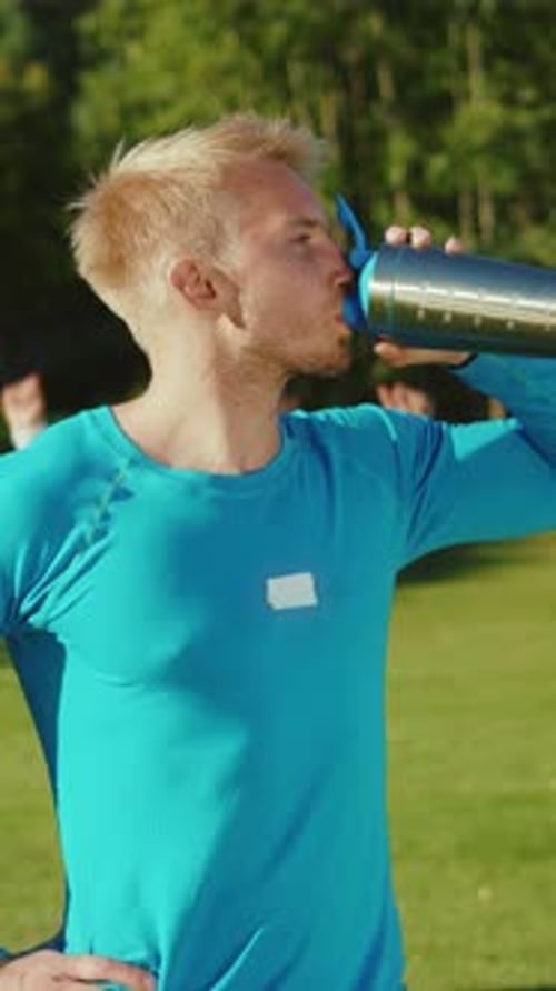 Man Drinking Water from Blue and Silver Bottle