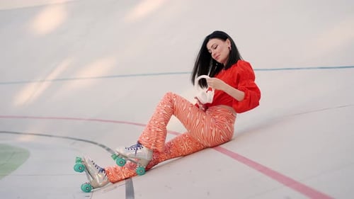 Lady in Retro Roller Skates Using Mobile and Headphones