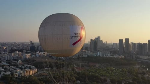 Aerial Shot Of Hot Air Balloon Descending Over Yarkon Park Against Sky In City