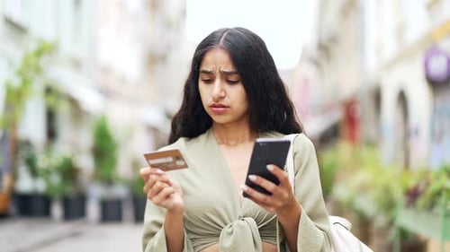 Confused Woman Holding Phone and Credit Card