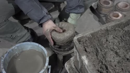 Plan large d'un ouvrier industriel façonnant un grand moule en argile sur un engrenage rotatif dans une usine